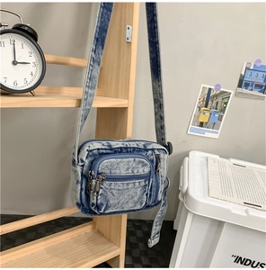 Detailed shot of a vintage washed denim crossbody bag hanging on a wooden display shelf