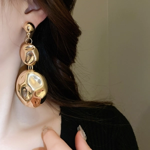 Detail of long gold earrings with three irregular hammered metal discs on model