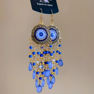 Detail of vintage bohemian tassel earrings with blue beads and golden filigree design
