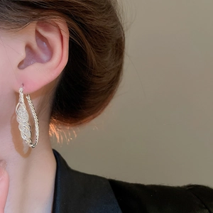 Detail of silver twisted hoop earring with sparkling zircon inlay on a female model