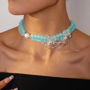 Detail of double-layer necklace with light blue beads, white pearl, and iridescent flowers