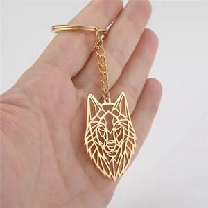 Detailed view of a gold geometric wolf head keychain held in hand for scale