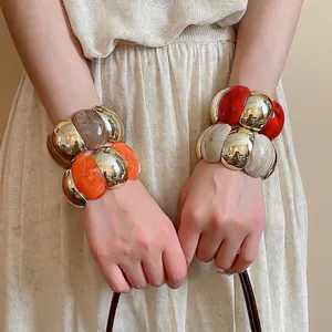 Exaggerated geometric bead bracelet with acrylic resin spheres and metallic gold finish