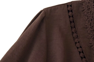Detail-Makroansicht von kaffeebraunem Baumwoll-Leinen-Stoff mit feiner Spitzen-Hohlstickerei