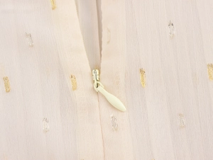 Detail of invisible zipper on beige chiffon fabric with gold and silver metallic threads