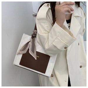 Detail of checkered tote bag with brown leather patch and printed silk scarf on handle