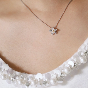 Detailed close-up of a silver daisy pendant necklace with a yellow center on a model