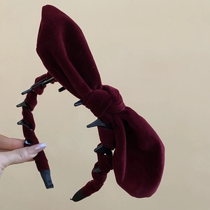 Detail of dark burgundy velvet headband featuring a large bow and internal non-slip teeth