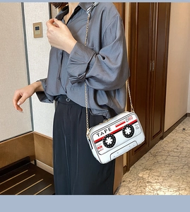 Lifestyle view of a vintage tape-shaped white crossbody bag with elegant gold chain strap
