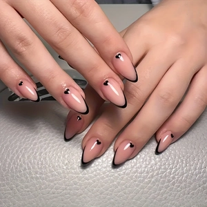 Nahaufnahme mandelförmiger French Nails mit schwarzen Spitzen und Herzmustern