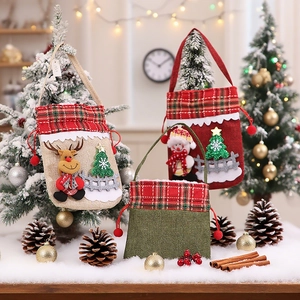 Three Christmas burlap gift bags with Reindeer and Snowman patterns on fake snow