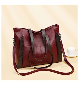 Detailed view of wine red leather tote bag with brown straps and soft grain texture