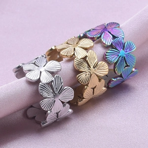 Detailed view of flower-shaped rings in silver, gold, and rainbow on purple silk fabric