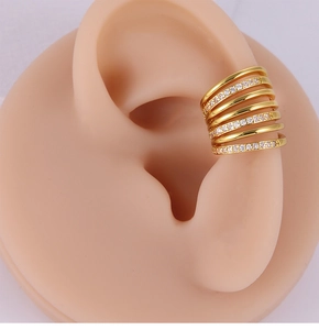 Close-up of gold layered ear cuff with white zircon stones on a model ear