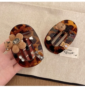 Detail of tortoise shell claw clip with plush bear, ribbon bow and diamond accents