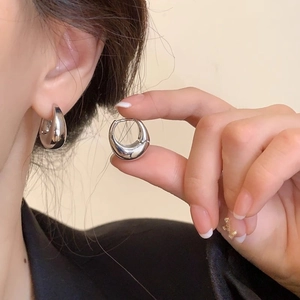 Close-up of polished silver teardrop earrings on model showcasing glossy metal finish