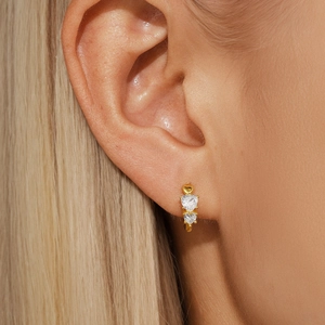 Macro shot of gold-plated heart-shaped zircon earrings worn by a model