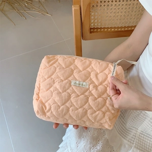Close-up of quilted heart pattern texture on beige portable cosmetic storage bag