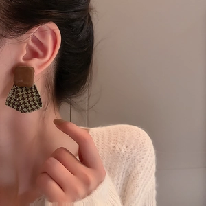 Detail of vintage square earrings with dark green houndstooth pattern fabric on model