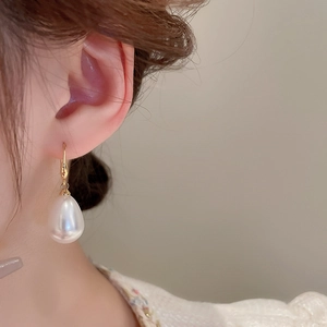 Close-up of model wearing water-drop pearl earrings with elegant gold hooks