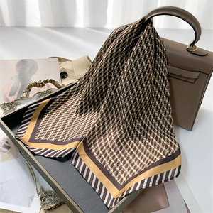 Détail d'un foulard en soie à motif chaîne noué sur un sac à main élégant