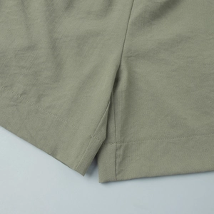 Close-up of sage green linen fabric texture and stitching on summer casual shorts