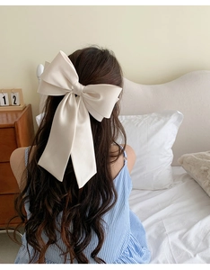Rear view of an oversized cream satin bow hair clip on a elegant hairstyle