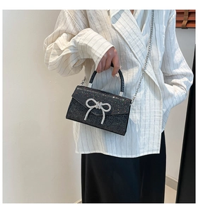 Détail du sac à main noir à paillettes avec nœud en strass argenté et chaîne
