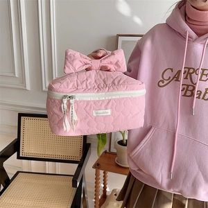 Détail macro d'une trousse de maquillage rose matelassée avec nœud et fermeture zippée