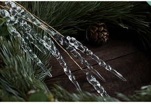 Macro shot of twisted acrylic icicle ornaments on pine needles and wooden background