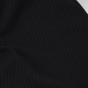 Close-up of black ribbed knit fabric showing detailed texture and elastic structure