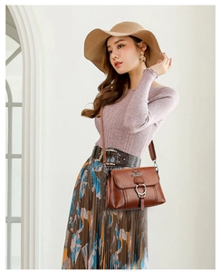 Detail of vintage brown leather crossbody bag featuring metal ring buckle and logo