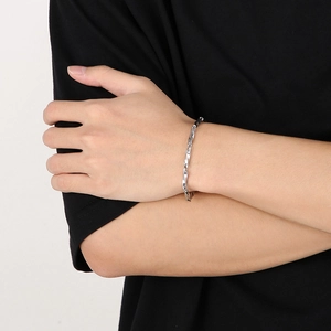 Détail d'un bracelet gourmette Mobius argenté au poignet avec texture métal polie