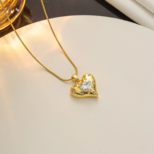 Detailansicht einer goldenen Herzkette mit Zirkonia-Inlay auf einem beigen Displayständer