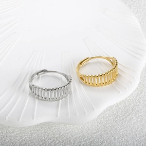 Detailed view of gold and silver open rings with hollow vertical stripe design on a tray