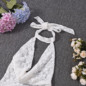 Flat lay of white lace halter romper with floral embroidery on a grey textured background