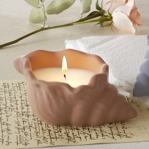 Primo piano di una candela profumata a forma di conchiglia rosa opaca su carta vintage
