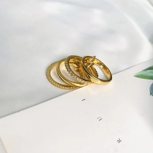 Artistic layout of gold ring set featuring sparkling pavé crystals on white silk background