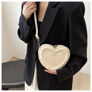 Detailed view of heart-shaped crossbody bag in cream PU leather with fashion lettering