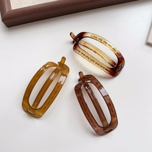 Three minimalist oval cutout hair clips with amber tortoise shell pattern on white surface