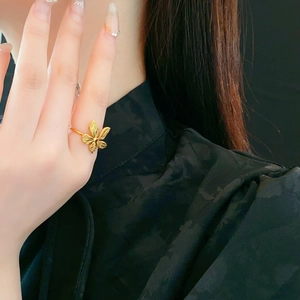 Detailed close-up of a floral golden stainless steel ring worn on a finger
