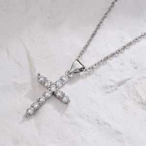 Classic silver cross necklace with clear zircon stones on a white textured background