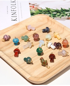 Macro shot of assorted natural crystal mushroom pendants with gold loops on wooden tray