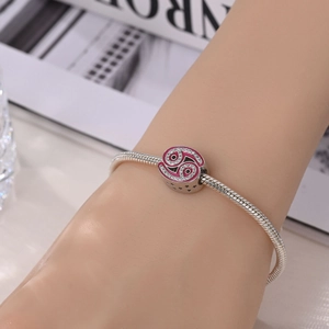 Detailed view of silver snake chain bracelet with pink crystal charm on a wrist