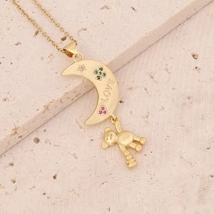 Close-up of a gold necklace with a moon and bear pendant featuring LOVE engraving
