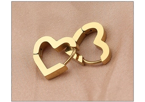 Detail of golden heart-shaped earrings on luxury champagne satin background