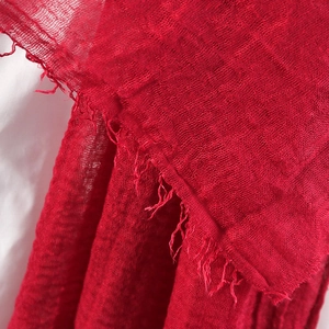 Macro detail of red crinkle cotton linen scarf showing soft fringe and woven texture