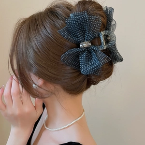 Macro detail of a mesh bow hair claw clip with rhinestones worn on a refined updo