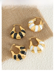 Detailed macro of C-shaped bread hoop earrings with black and white enamel in 18K gold finish