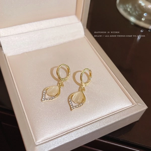 Detail view of vintage cat eye stone water drop earrings in a beige jewelry box